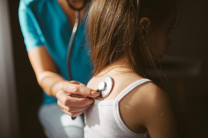 Médica auscultando a una niña en consulta